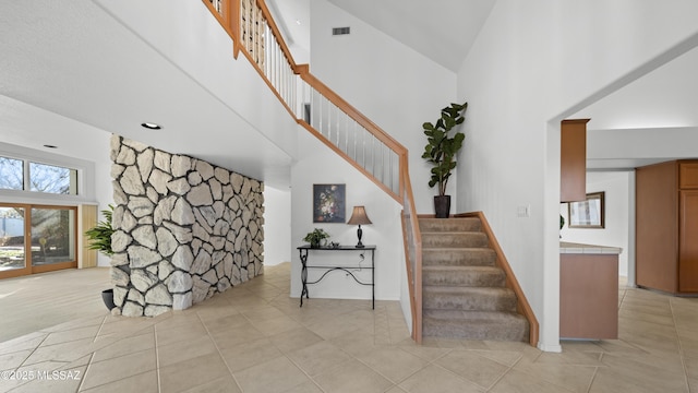 stairway featuring a towering ceiling and tile patterned floors