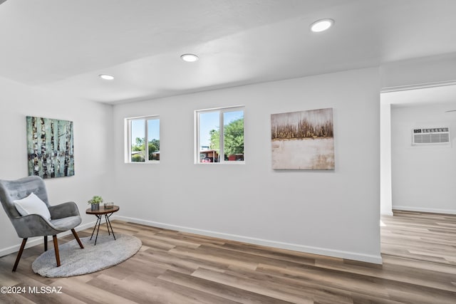 living area with a wall unit AC and wood-type flooring