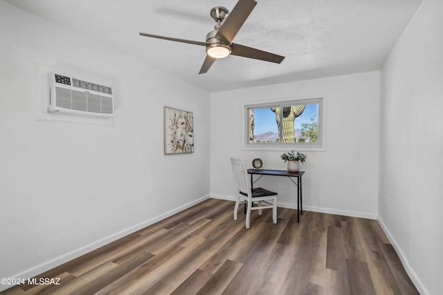 home office with dark wood-type flooring, a wall unit AC, and ceiling fan