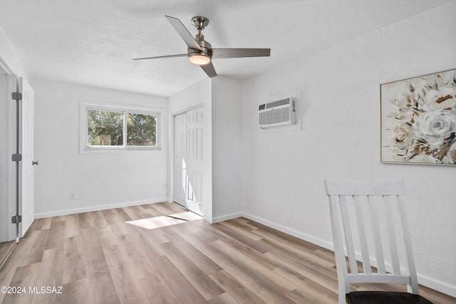 unfurnished bedroom featuring a closet, ceiling fan, a wall mounted AC, and light wood-type flooring