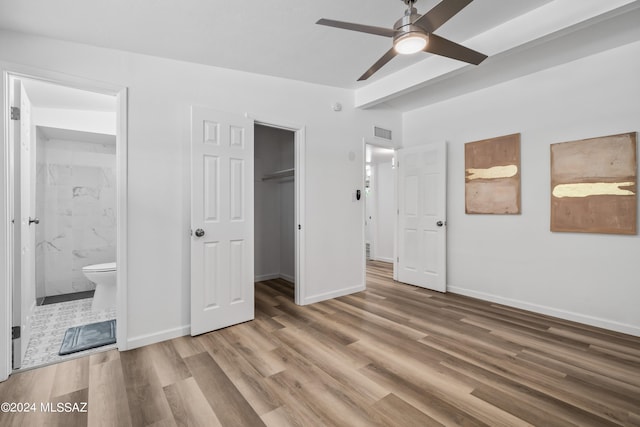 unfurnished bedroom with a closet, ensuite bathroom, ceiling fan, and hardwood / wood-style floors