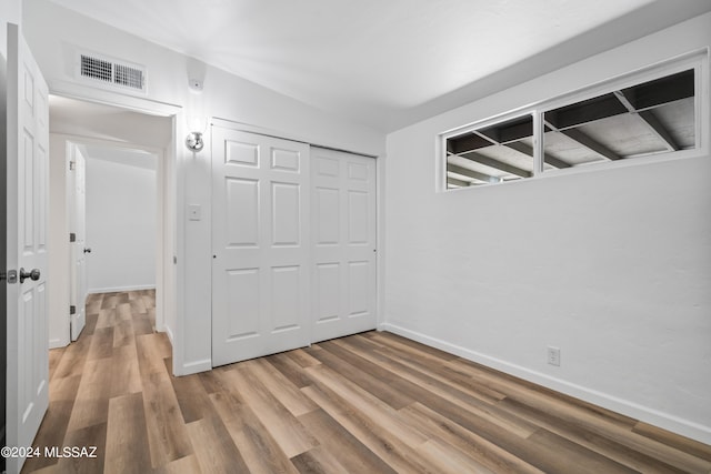 unfurnished bedroom with hardwood / wood-style flooring and a closet