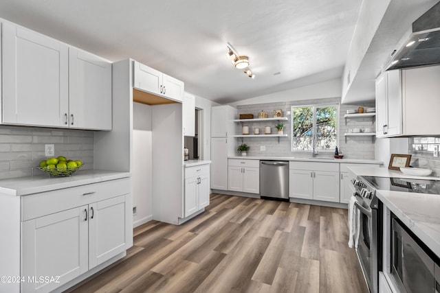 kitchen with decorative backsplash, white cabinets, stainless steel appliances, and vaulted ceiling