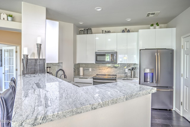 kitchen featuring dark hardwood / wood-style flooring, white cabinets, light stone counters, and stainless steel appliances