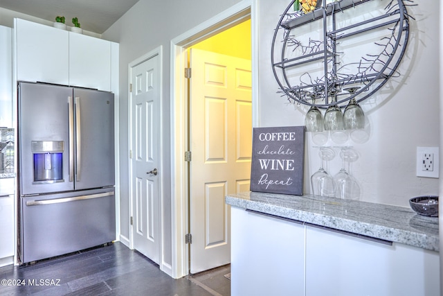 kitchen with dark wood-type flooring, white cabinetry, stainless steel fridge with ice dispenser, and light stone counters