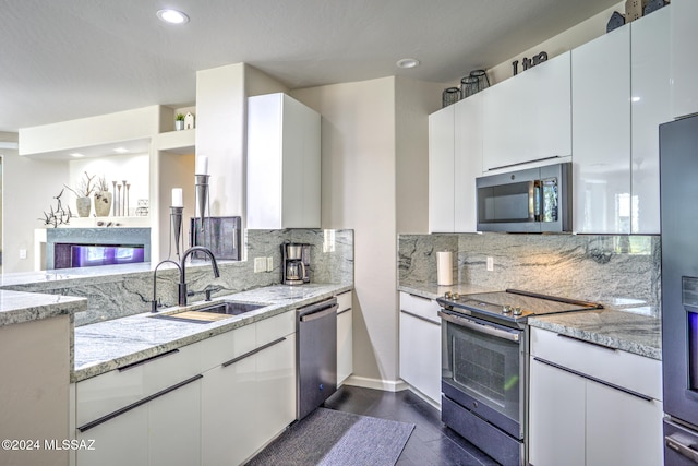 kitchen with white cabinets, sink, light stone counters, and appliances with stainless steel finishes