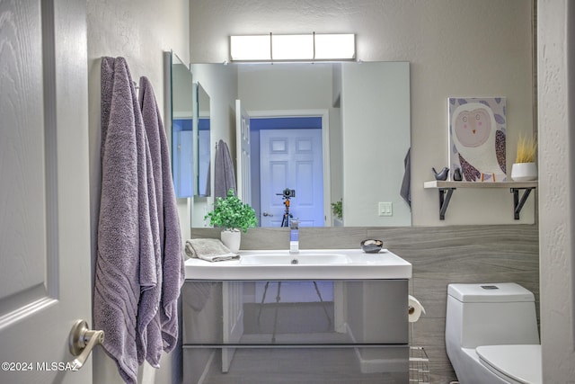 bathroom featuring vanity, toilet, and tile walls