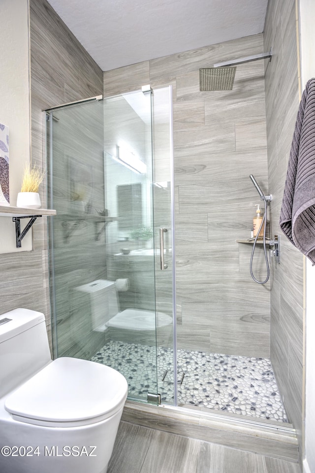 bathroom featuring toilet, an enclosed shower, and tile walls