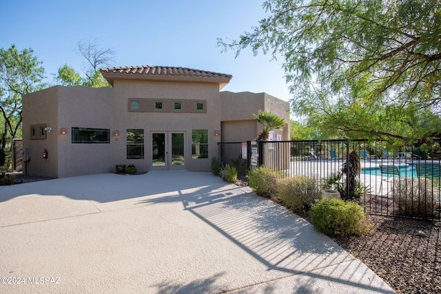 back of house with a fenced in pool, a patio, and french doors