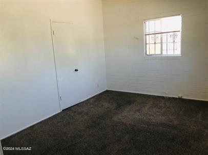 unfurnished room with dark carpet