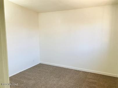 spare room featuring baseboards and dark colored carpet