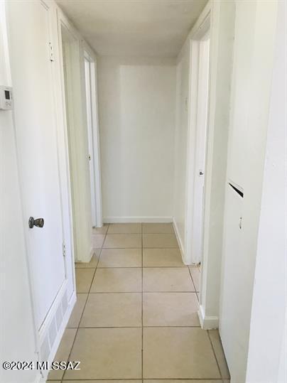 hall featuring baseboards and light tile patterned flooring