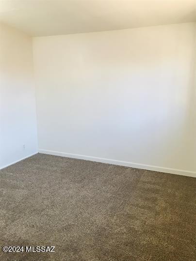 unfurnished room featuring dark colored carpet