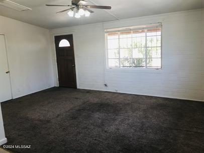 interior space featuring ceiling fan and brick wall