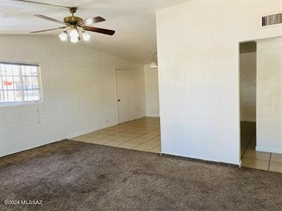 spare room featuring ceiling fan, lofted ceiling, carpet, and visible vents