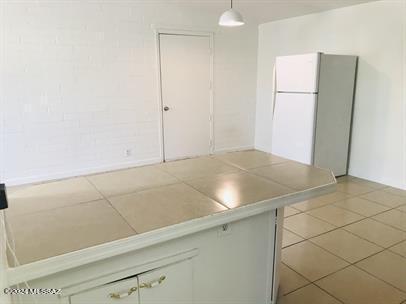 kitchen with light tile patterned flooring, hanging light fixtures, and white fridge