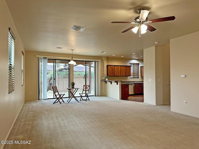 interior space with dishwasher, light colored carpet, hanging light fixtures, and ceiling fan