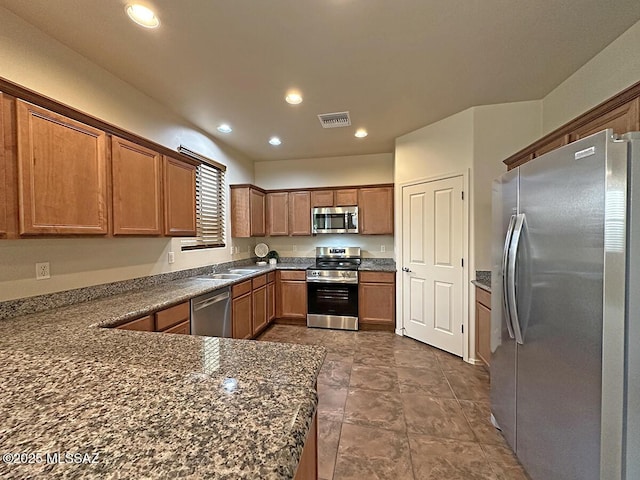 kitchen featuring dark stone countertops, sink, kitchen peninsula, and stainless steel appliances