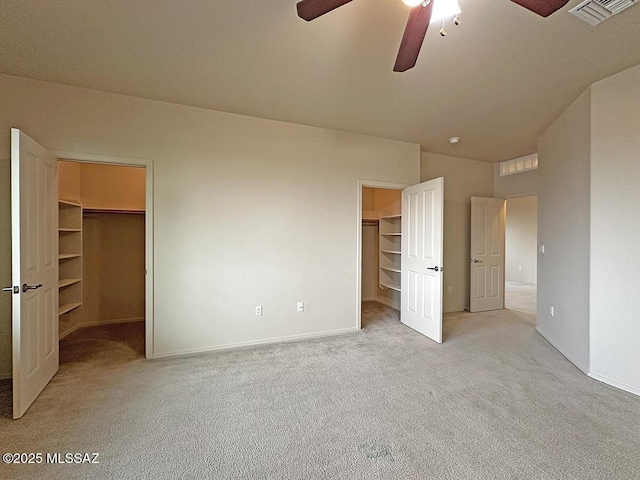 unfurnished bedroom featuring ceiling fan, a walk in closet, light carpet, and a closet