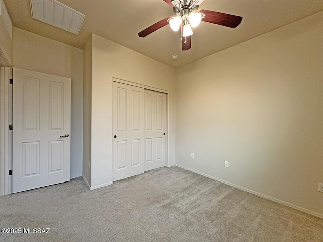 unfurnished bedroom featuring light carpet, a closet, and ceiling fan