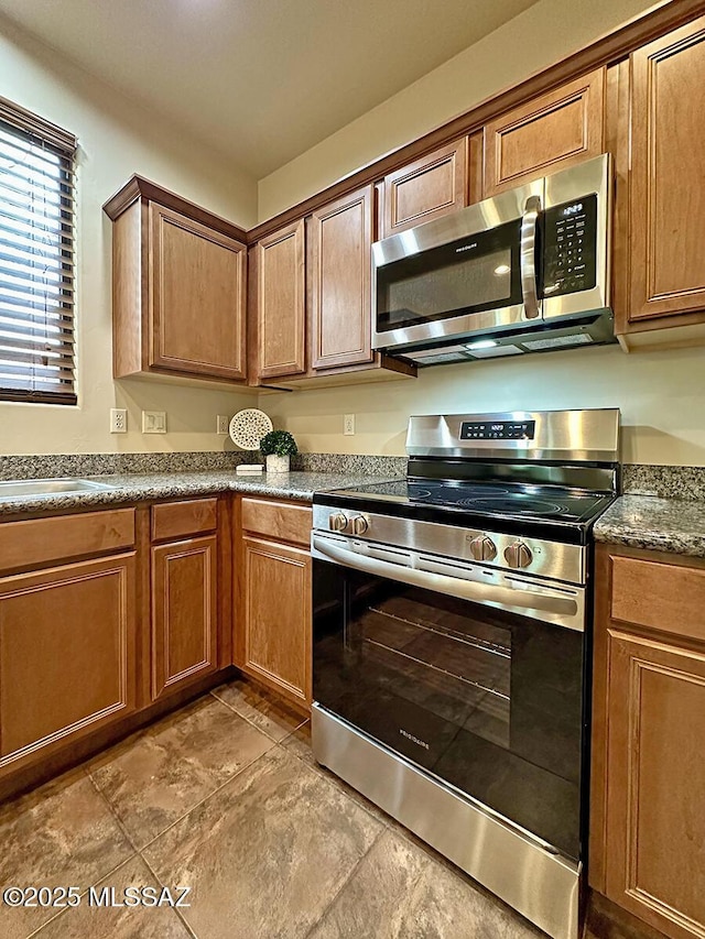 kitchen with stainless steel appliances, dark stone counters, and sink