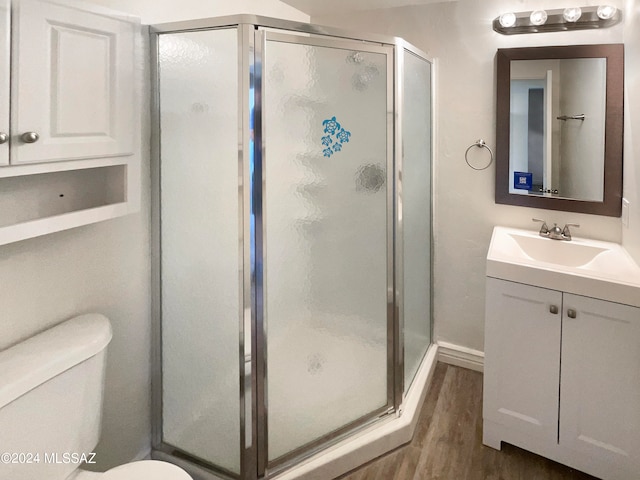 bathroom with walk in shower, wood-type flooring, vanity, and toilet