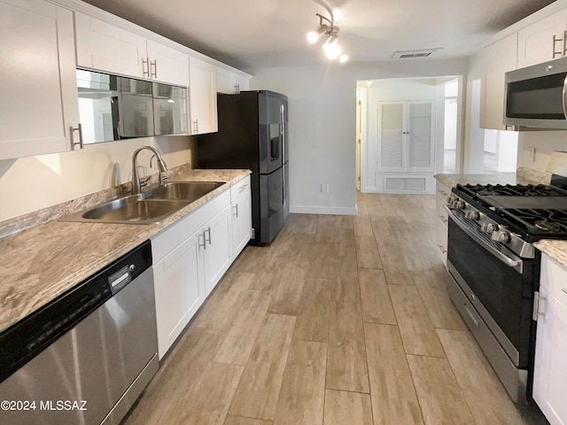 kitchen featuring appliances with stainless steel finishes, light wood-type flooring, sink, and white cabinetry