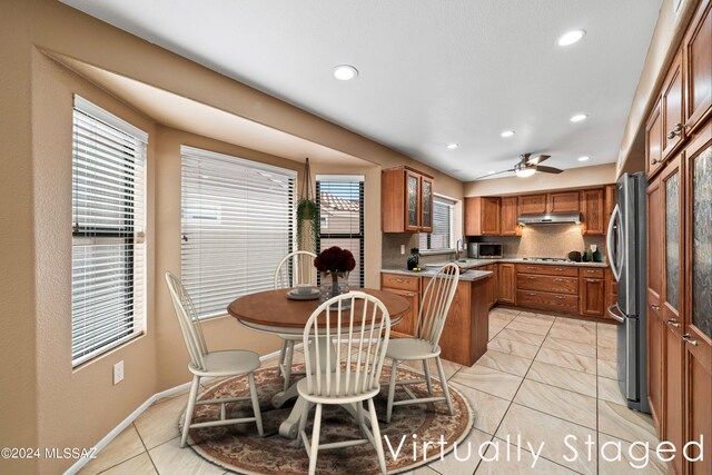 kitchen featuring appliances with stainless steel finishes, decorative backsplash, sink, and ceiling fan