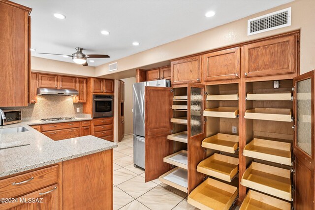 kitchen with decorative backsplash, kitchen peninsula, stainless steel appliances, ceiling fan, and sink