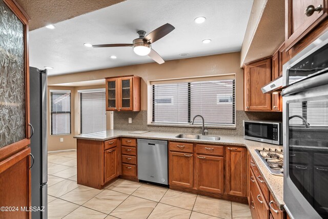 kitchen featuring tasteful backsplash, light stone countertops, stainless steel appliances, ceiling fan, and sink