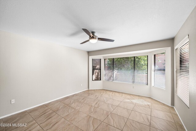 bedroom featuring ceiling fan, light tile patterned floors, and a textured ceiling