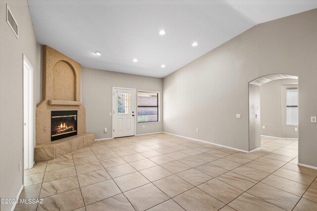 living room with a large fireplace, lofted ceiling, and light tile patterned floors