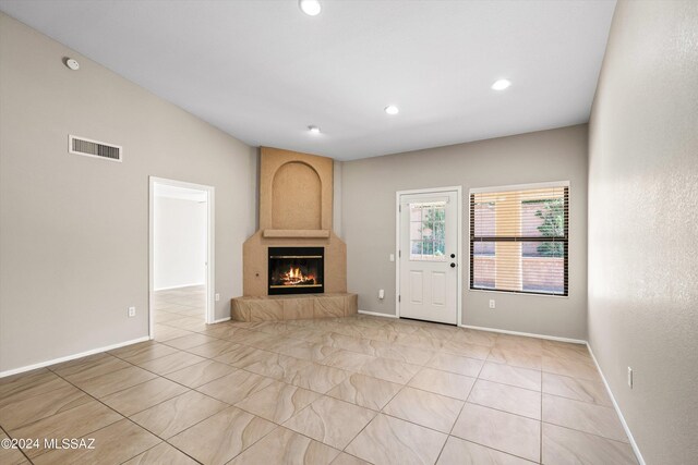 unfurnished living room featuring vaulted ceiling, light tile patterned floors, and a fireplace