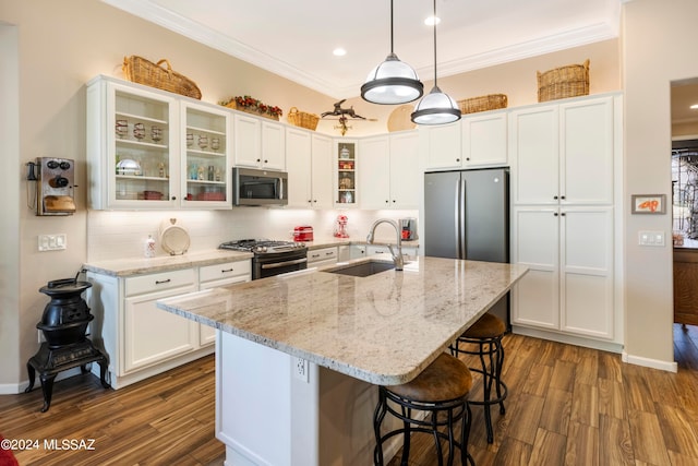 kitchen with an island with sink, appliances with stainless steel finishes, dark hardwood / wood-style floors, and white cabinetry