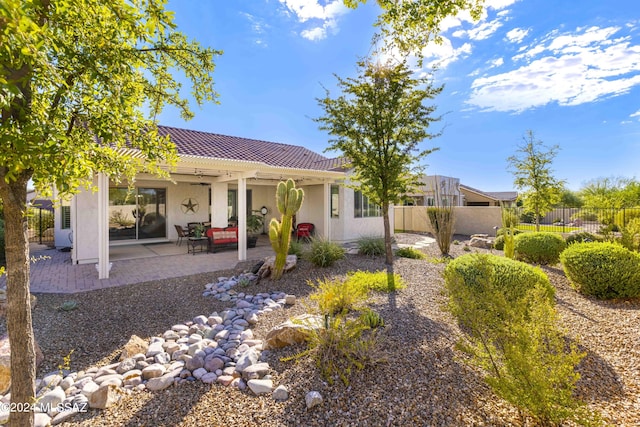 rear view of house featuring a tiled roof, fence, a patio, and stucco siding