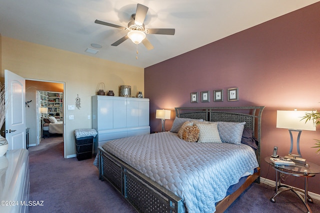 bedroom featuring a spacious closet, a closet, dark carpet, and ceiling fan