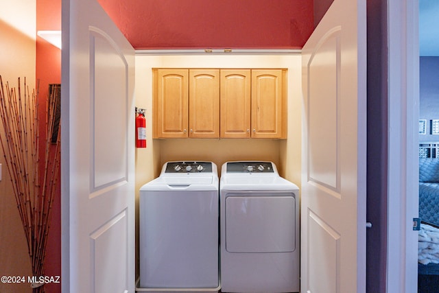 laundry room with washing machine and clothes dryer and cabinets