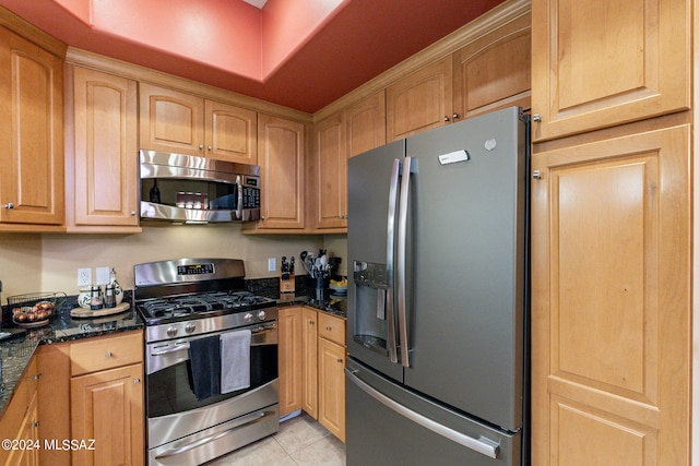 kitchen featuring dark stone countertops, light tile patterned floors, and stainless steel appliances