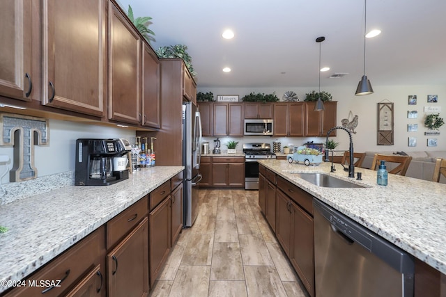 9745 S Desert Flint Dr, Tucson, AZ 85747 - kitchen with stainless steel appliances, a sink, visible vents, light stone counters, and hanging light fixtures