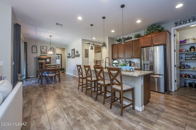 9745 S Desert Flint Dr, Tucson, AZ 85747 - kitchen featuring a barn door, visible vents, decorative light fixtures, stainless steel fridge, and a breakfast bar area