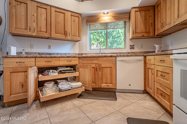 kitchen featuring white appliances, light tile patterned flooring, stone countertops, and sink