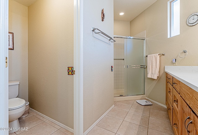 bathroom featuring tile patterned flooring, a shower with door, vanity, and toilet