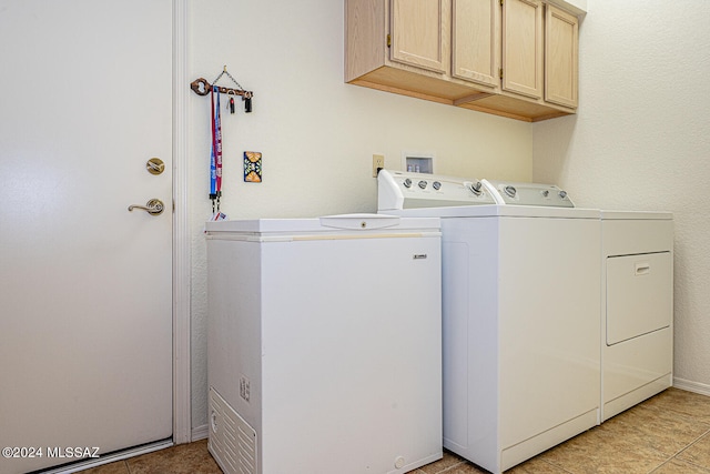 laundry area with separate washer and dryer, light tile patterned floors, and cabinets