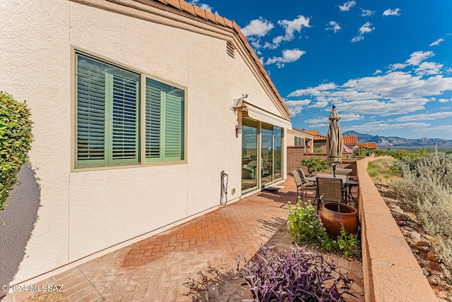 view of home's exterior with a mountain view and a patio area