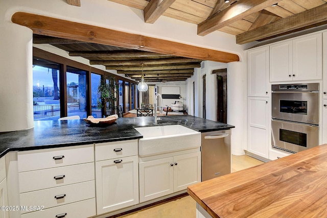 kitchen with wood counters, wooden ceiling, white cabinets, sink, and stainless steel appliances