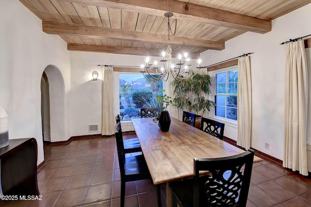 dining space with beamed ceiling, dark tile patterned flooring, wooden ceiling, and a notable chandelier