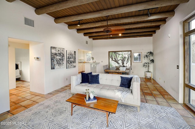 living room featuring beam ceiling, a towering ceiling, wooden ceiling, and light tile patterned flooring