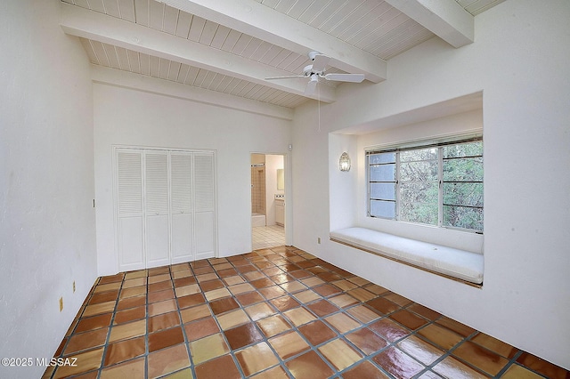 unfurnished bedroom featuring beam ceiling, dark tile patterned flooring, a closet, and ceiling fan