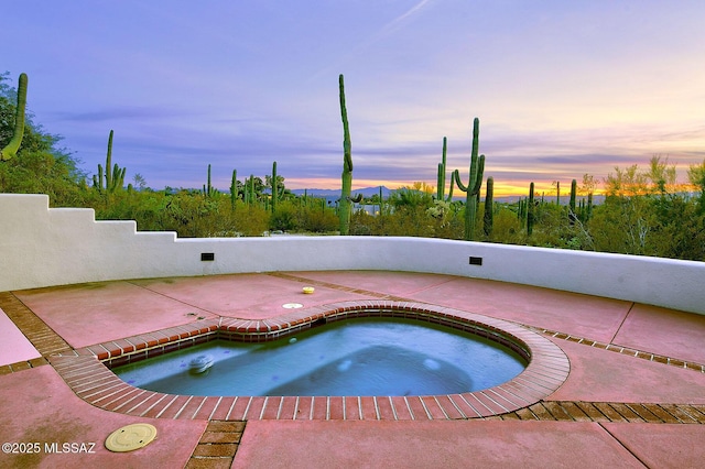 pool at dusk with an in ground hot tub