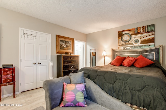 bedroom with a textured ceiling, a closet, and light hardwood / wood-style floors